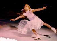 a girl in a white dress skates on an ice rink