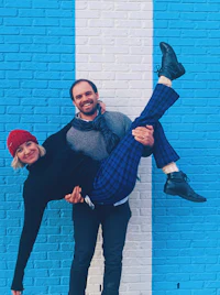 a man and woman posing in front of a blue wall