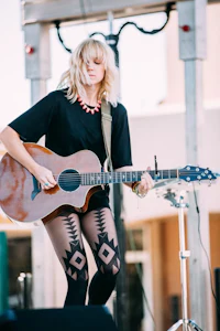 a woman in tights playing an acoustic guitar