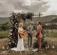 a bride and groom playing guitar at an outdoor wedding