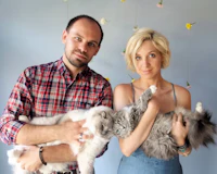 a man and woman posing for a photo with two cats