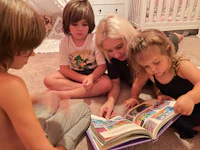 a woman reading a book to a group of children