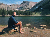 a man sitting on a rock next to a lake