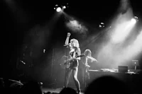 a black and white photo of a woman on stage with a guitar