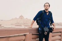 a man with a camera standing on a bridge